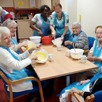 Photograph of the cookery group sat around a table with mixing bowls