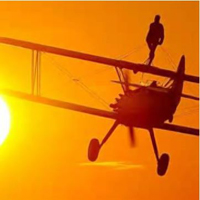 Photogrpah of someone standing on top of a plane doing a wing walk