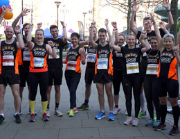 Photo of a group of people standing in a row wearing their SRSB running vests and cheering