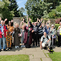 Group photo of everyone at Graves Park Sensory Garden on the opening day with their hands in the air
