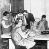 Old black and white photo of children at school making baskets