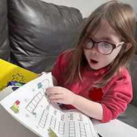 Photo of a young girl looking surprised as she opens an activity pack
