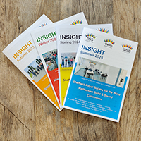 Image is a photo of 4 different coloured newsletters for the 4 different seasons they are sent out: orange for autumn, red for winter, yellow for spring, blue for summer