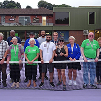Photo of some people at the tennis standing on the court in a group