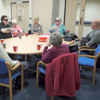 Photogrpah of people sat around the table in a meeting with a cuppa