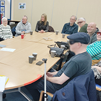 Photo of some people sat around a table in a previous group